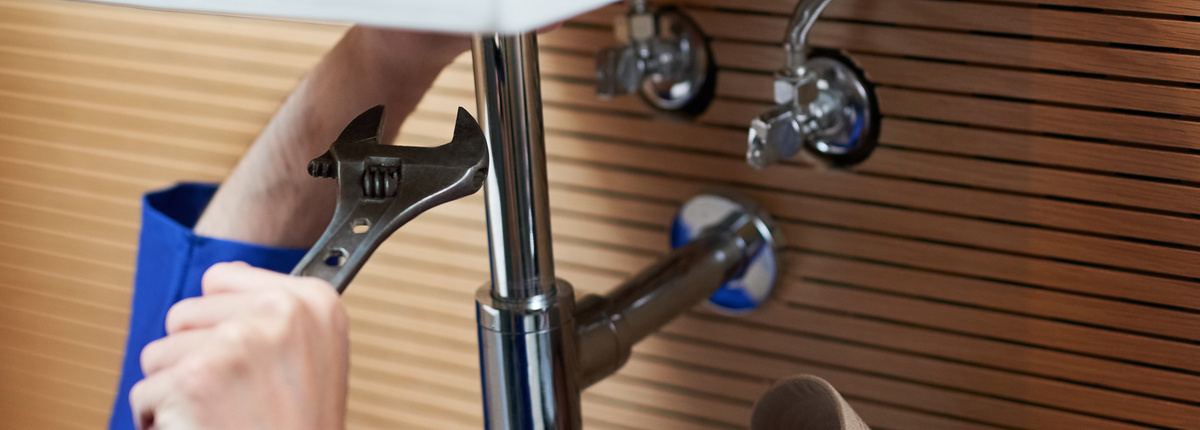 mp64586585 handyman plumber and tools in bathroom sink with wrench